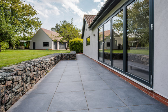 modern patio with glass doors and landscaped garden featuring stone wall and reflection on windows