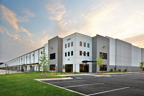 large modern warehouse building with parking lot and landscaped greenery in the foreground showcasing commercial space for businesses and two-story design