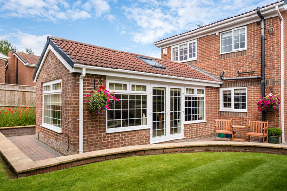 brick house extension with large windows and flower pots in the garden inviting outdoor living space and natural light