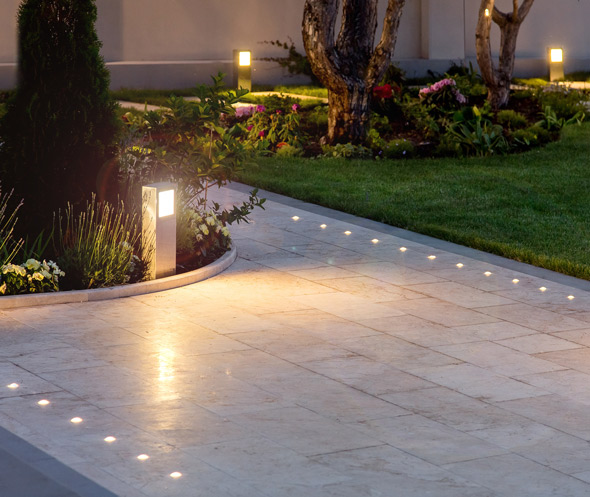 landscaped garden pathway with modern lighting fixtures illuminating the stone walkway showcasing beautiful plants and greenery for outdoor ambiance